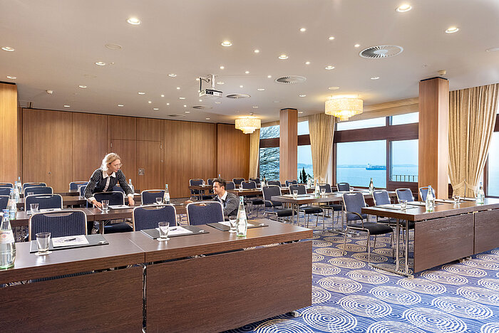 Saal Kiel im Maritim Hotel Kiel, großer Konferenzraum mit Meerblick, freundliches Personal richtet die Tische ein.