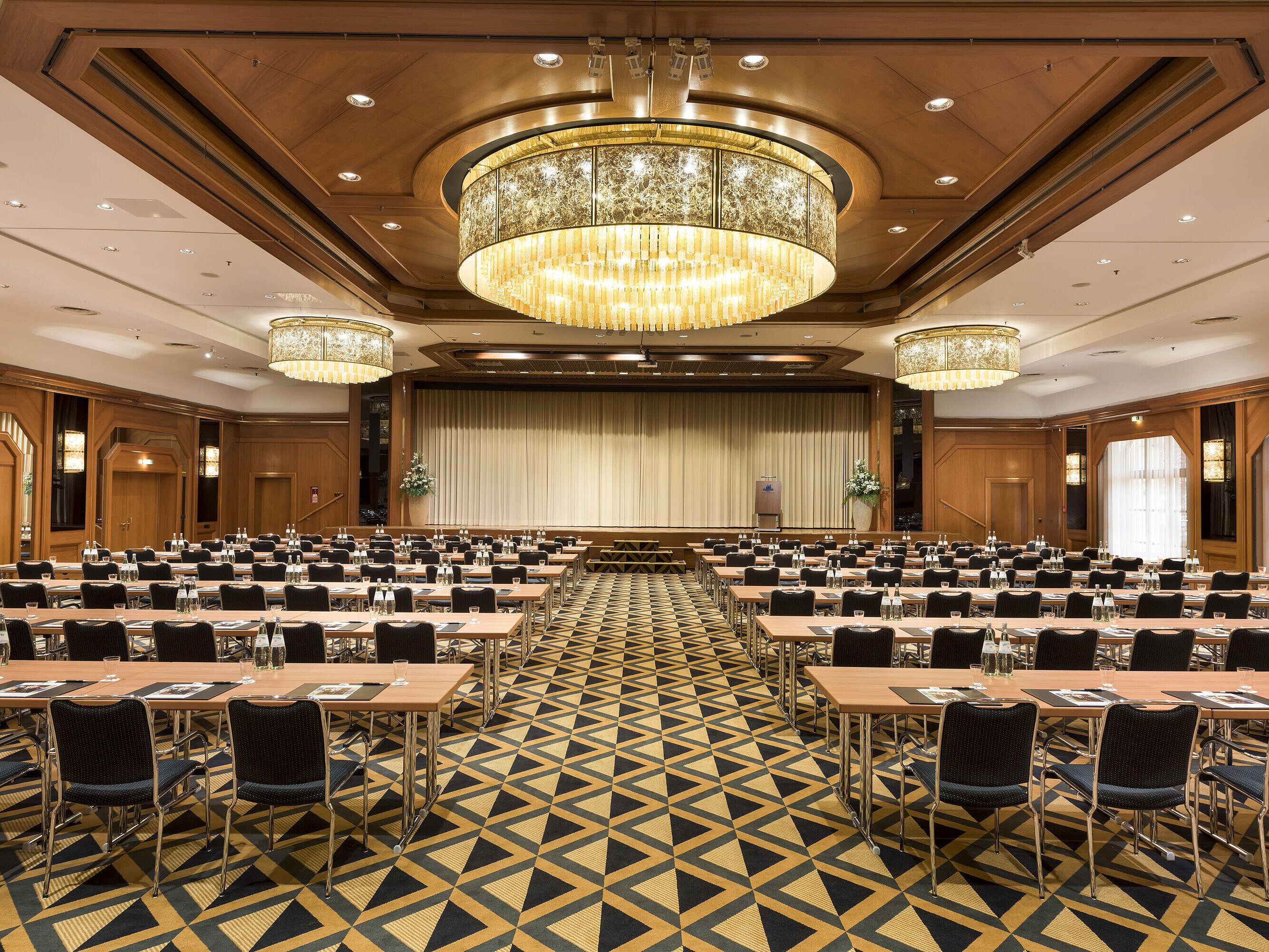 Eleganter Tagungssaal mit Bühne, Kronleuchtern und moderner Bestuhlung im Maritim Hotel Königswinter.