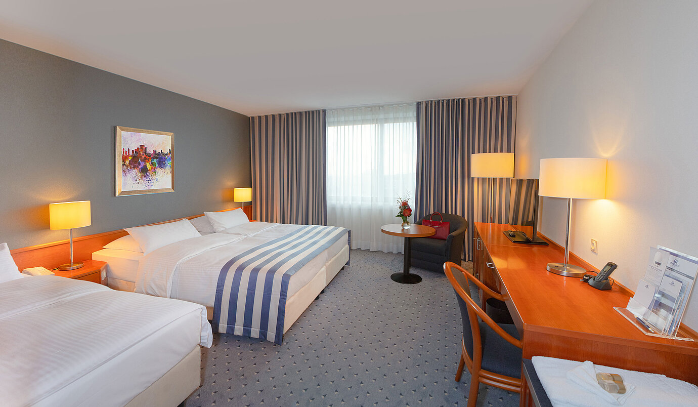 Familienzimmer im Maritim Hotel Ulm mit gemütlicher Sitzecke und warmen Farbtönen.