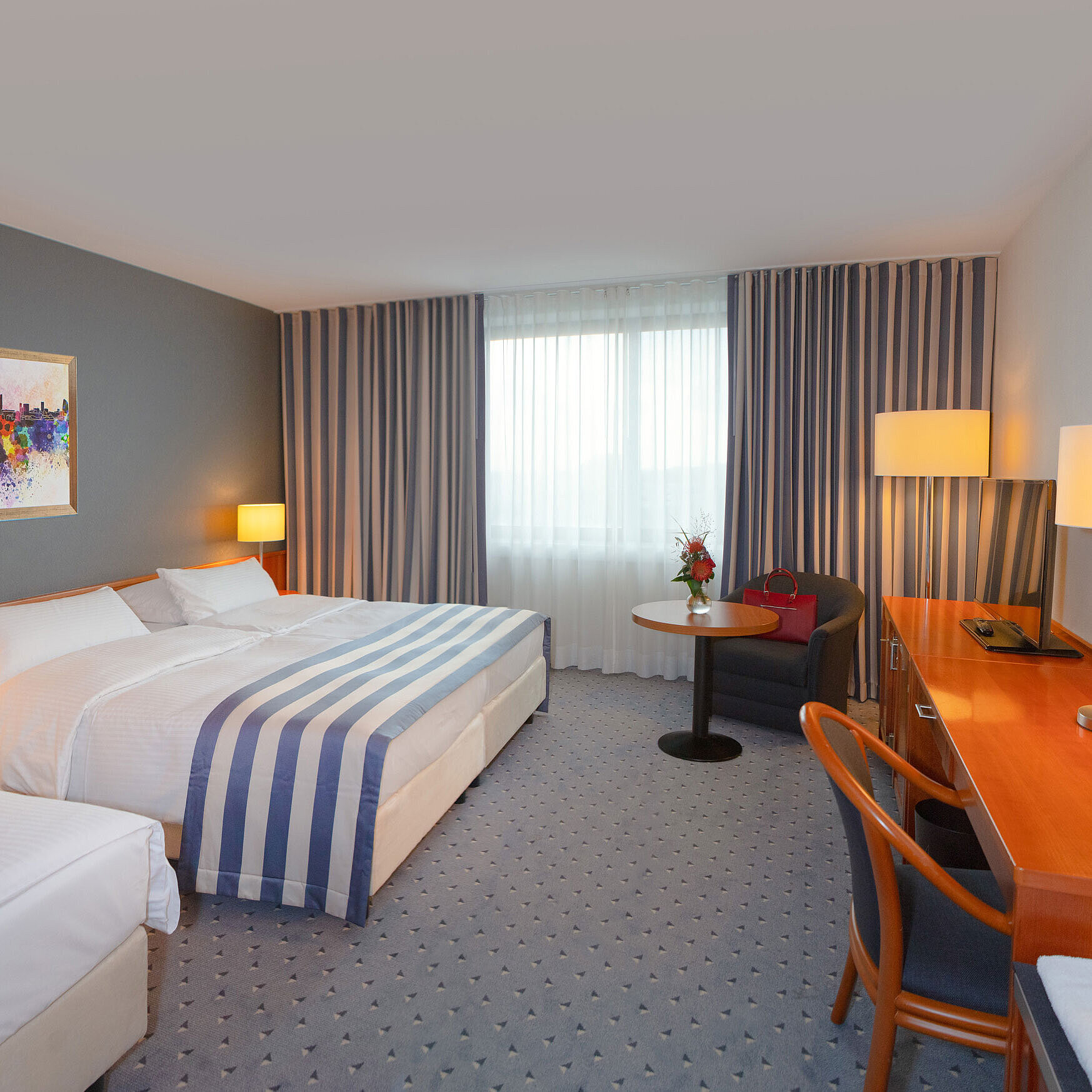 Familienzimmer im Maritim Hotel Ulm mit gemütlicher Sitzecke und warmen Farbtönen.