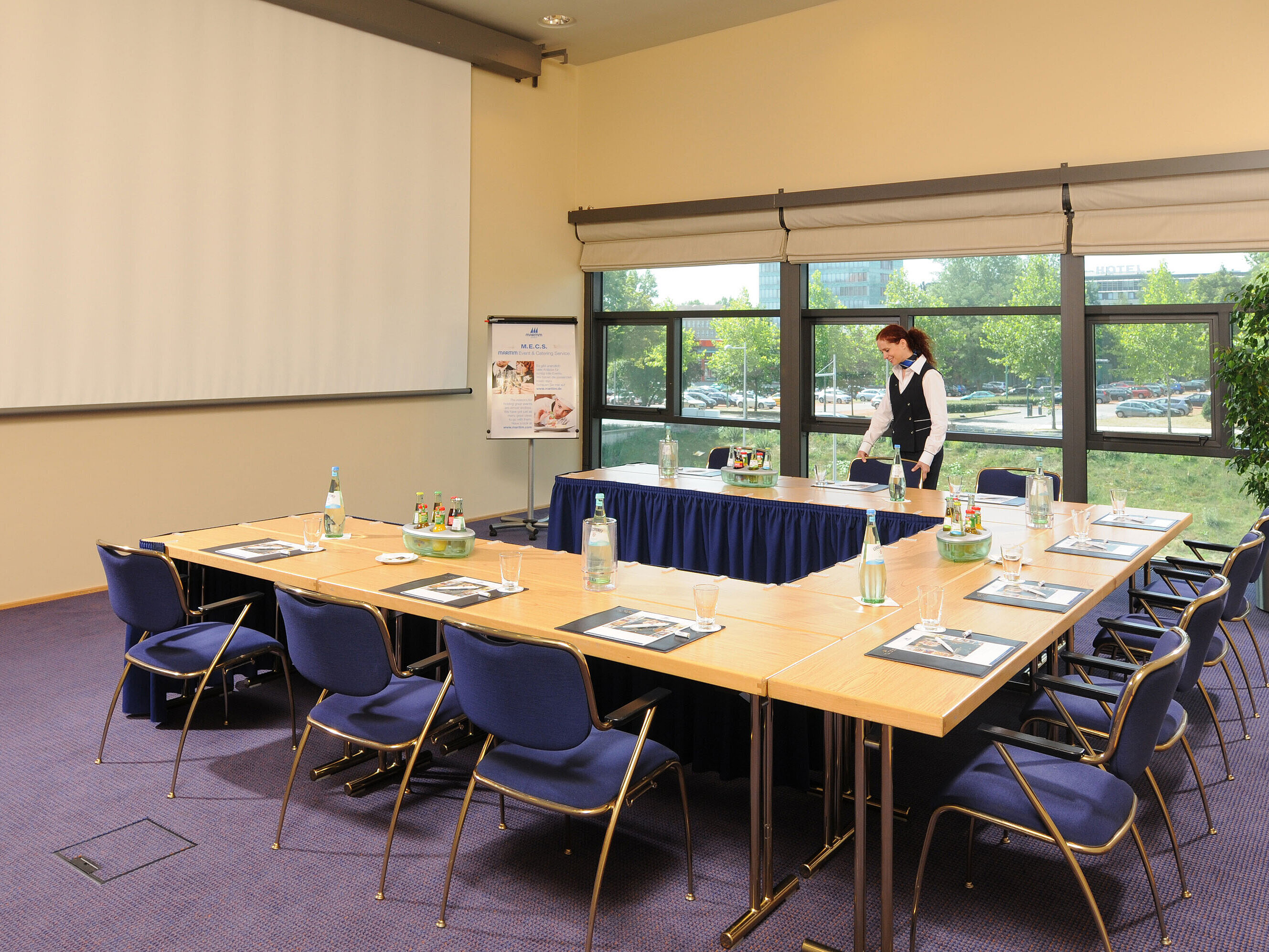 Tagungsraum im Maritim Hotel Dresden mit U-förmiger Tischanordnung, Präsentationsleinwand und Vorbereitungen für ein Meeting.