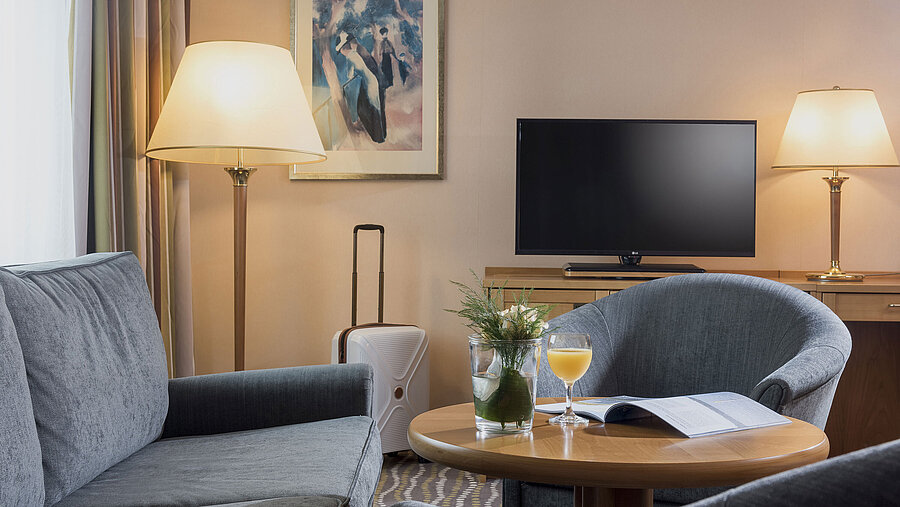 Komfortables Hotelzimmer mit Schreibtisch, Flachbildfernseher und Sitzecke mit Tageslicht und stilvollem Interieur.