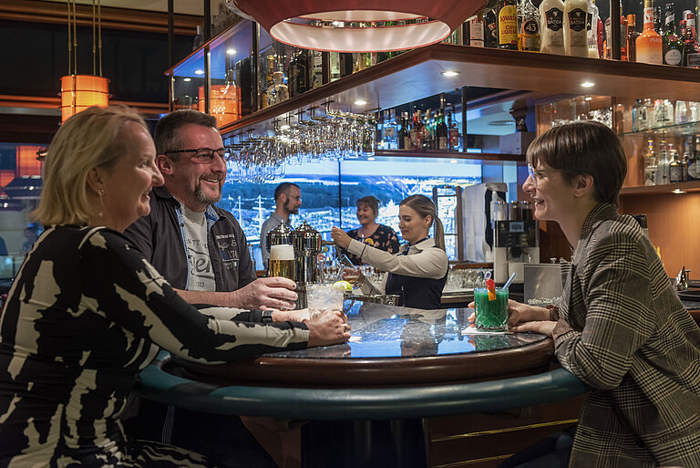 Gäste unterhalten sich an der Bar und genießen Drinks im Maritim Hotel Travemünde