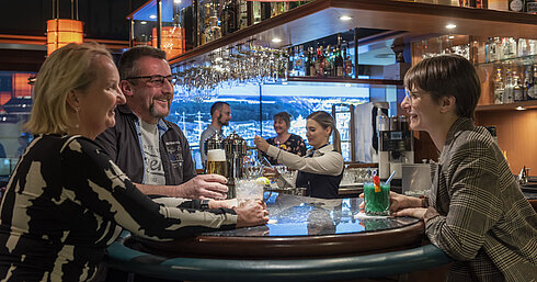 Gäste unterhalten sich an der Bar und genießen Drinks im Maritim Hotel Travemünde