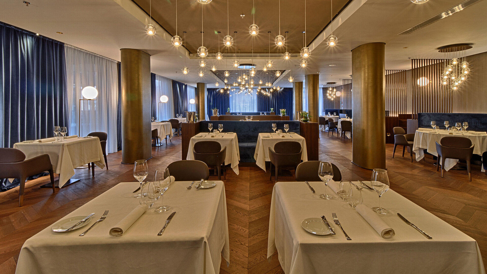 Großzügiges Restaurant mit stilvoller Beleuchtung, Holzboden und gedeckten Tischen im Maritim Hotel Plaza Tirana