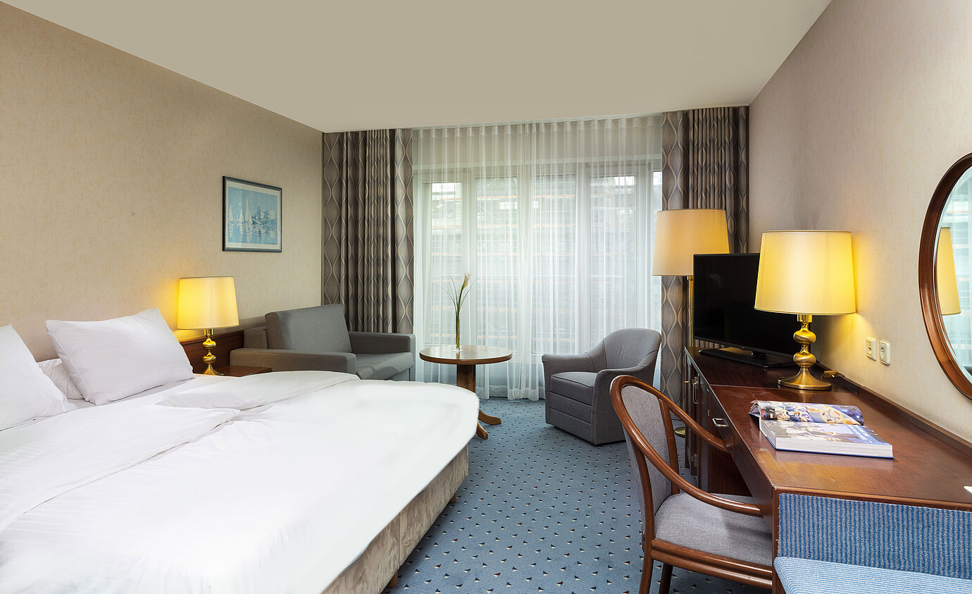 Helles Familienzimmer im Maritim Hotel Köln mit Doppelbett, Schreibtisch, Fernseher,Sesseln und großen Fenstern mit Vorhängen