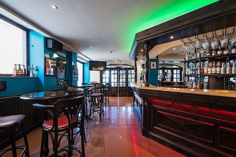 Stilvolle Pub-Bar im Maritim Antonine Hotel & Spa Malta mit dunklem Holzinterieur, Spirituosenauswahl und gemütlichen Sitzbereichen.
