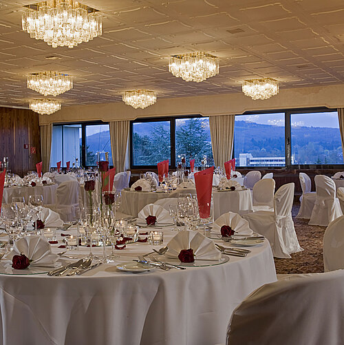Großer Saal mit runden Tischen, eleganter Deko und Blick ins Grüne im Maritim Hotel Bad Salzuflen