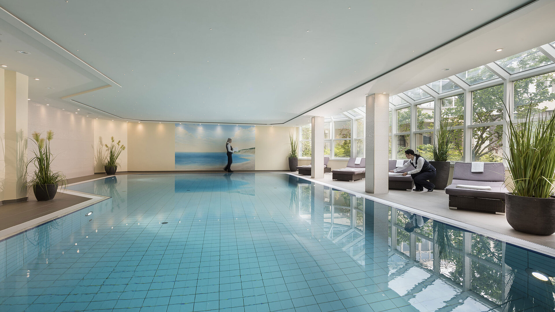 Schwimmbad Großer Innenpool im Maritim Hotel Würzburg mit Glasfront, Liegen und freundlichem Service.
