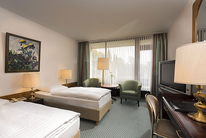 Doppelzimmer mit zwei Betten, Sesseln, Schreibtisch und Balkon im Maritim Hotel Bad Salzuflen