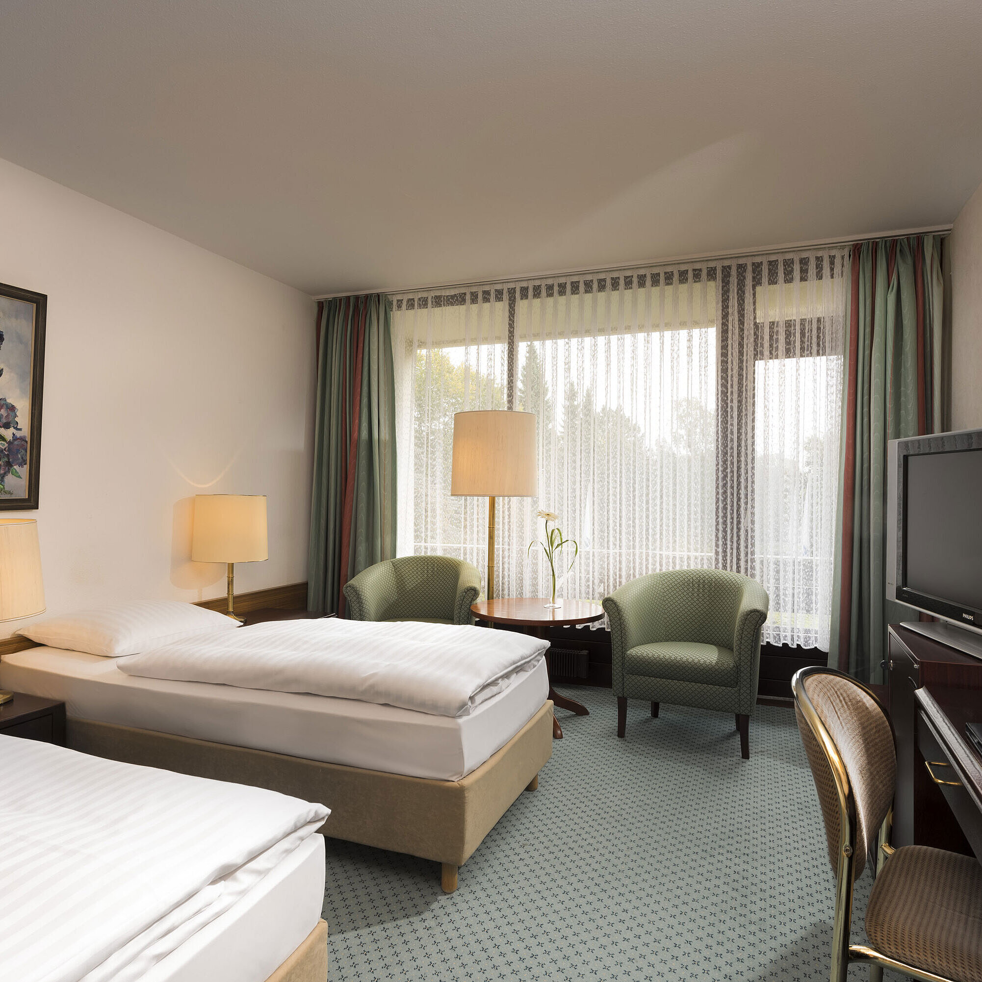 Doppelzimmer mit zwei Betten, Sesseln, Schreibtisch und Balkon im Maritim Hotel Bad Salzuflen