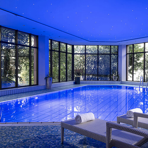 Der stilvolle Innenpool des Maritim Hotel Bad Homburg lädt mit angenehmer Beleuchtung und bequemen Liegen zum Entspannen ein.
