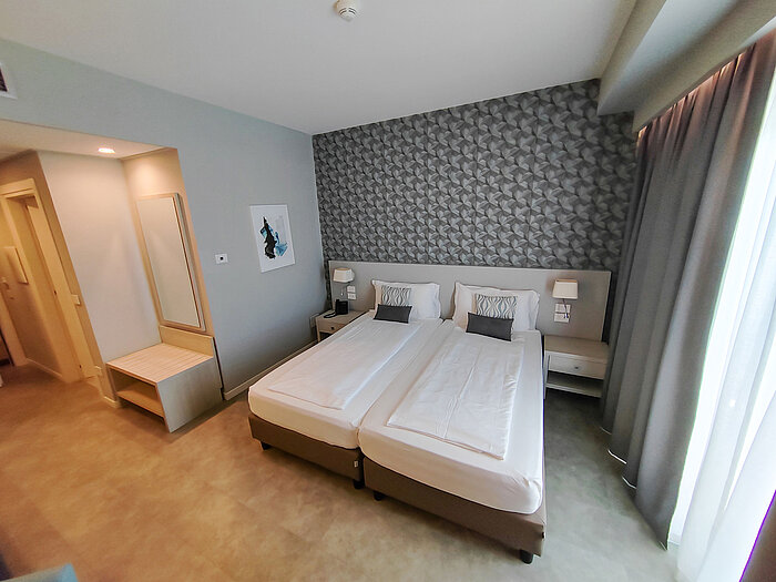 Modernes Hotelzimmer im Maritim Resort Calabria mit Twin-Bett, Schreibtisch und Spiegel