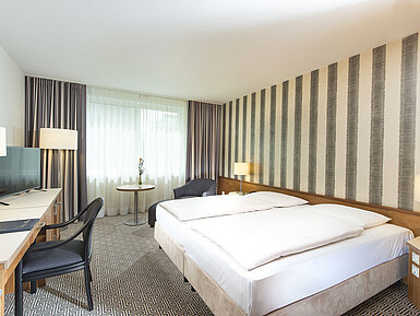 Modernes Hotelzimmer mit gestreifter Wand, Doppelbett und Schreibtisch im Maritim Hotel Stuttgart