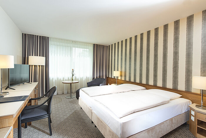 Modernes Hotelzimmer mit gestreifter Wand, Doppelbett und Schreibtisch im Maritim Hotel Stuttgart