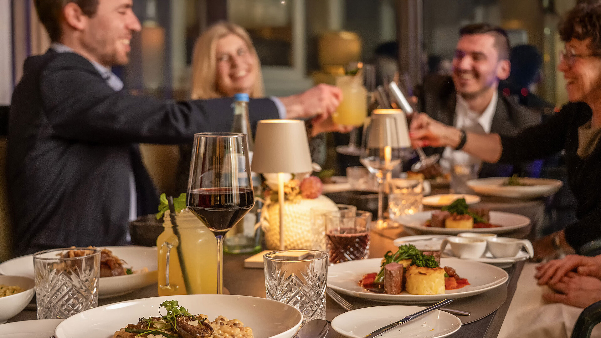 Gäste genießen ein gemeinsames Dinner im Restaurant an einem stilvoll gedeckten Tisch