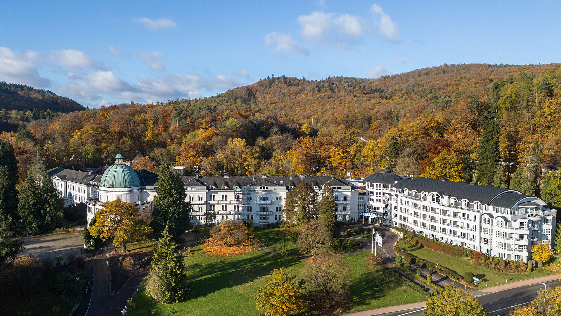 Außenansicht des Maritim Hotel Bad Wildungen, umgeben von Park, Bäumen und herbstlichem Waldpanorama.