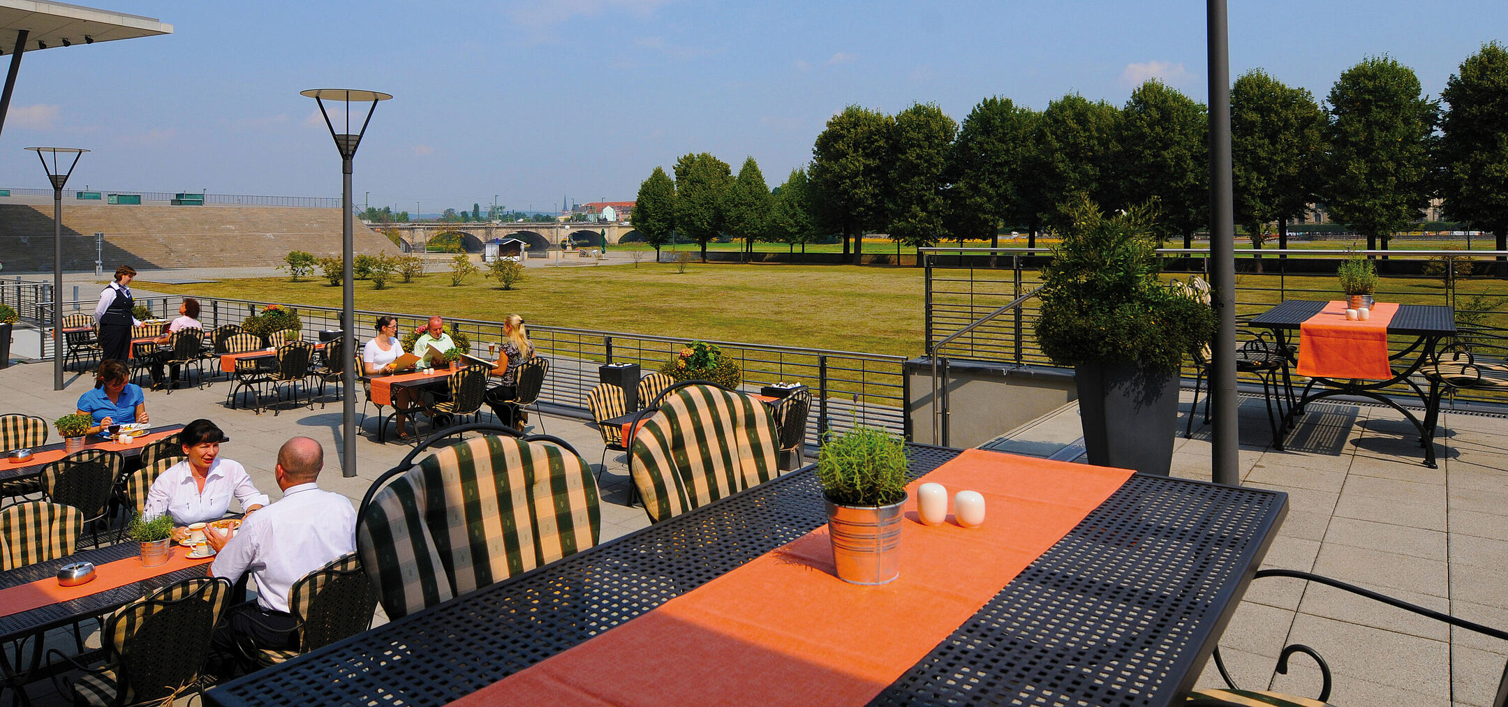 Sonnige Terrasse des Restaurants Wintergarten im Maritim Hotel Dresden mit Blick auf die Elbwiesen.