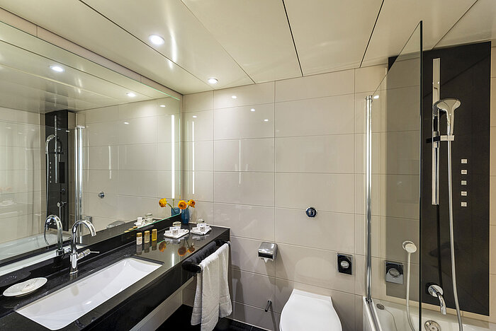 Modernes Badezimmer mit Badewanne, großem Spiegel, eleganter Armatur und hochwertigen Annehmlichkeiten im Maritim Hotel Ulm.