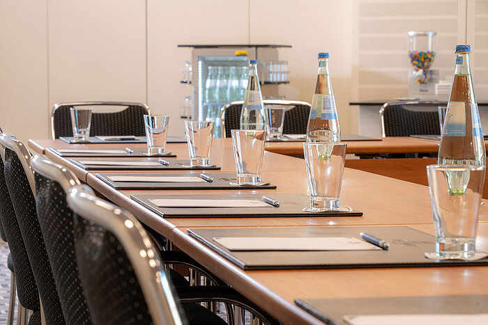 Gedeckter Konferenztisch im Maritim Hotel Bad Homburg mit Wasser, Gläsern und Notizblöcken.
