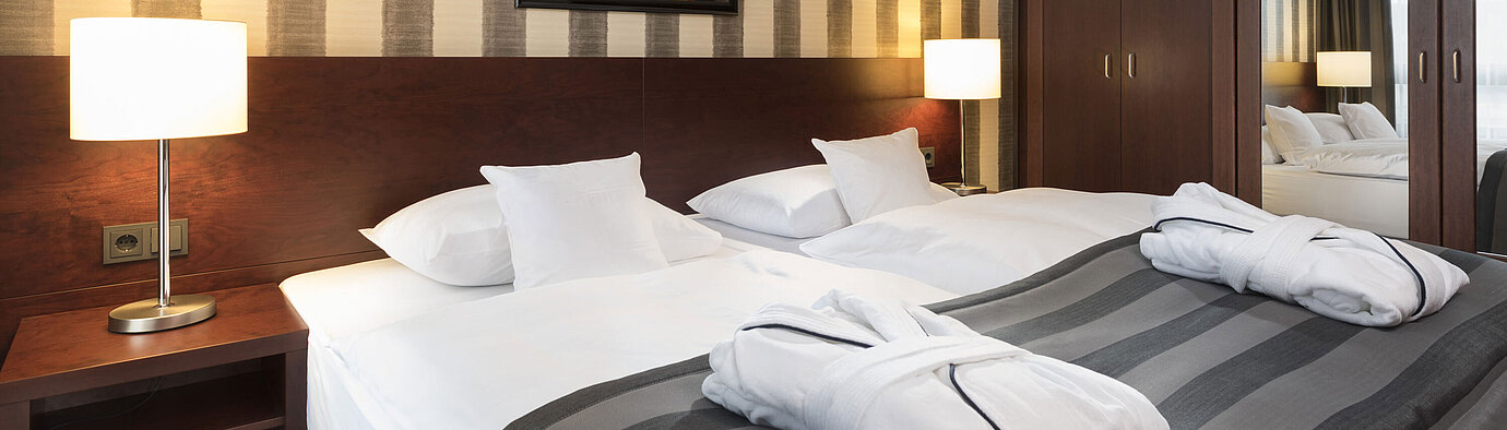 Modernes Doppelzimmer mit gemütlichem Bett, Bademänteln und stilvollem Interieur im Maritim Hotel Königswinter.