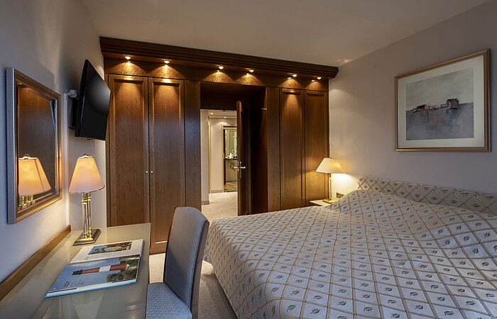 Elegante Präsidentensuite im Maritim Hotel Kiel mit großem Bett, Schreibtisch und warmem Holzdekor.
