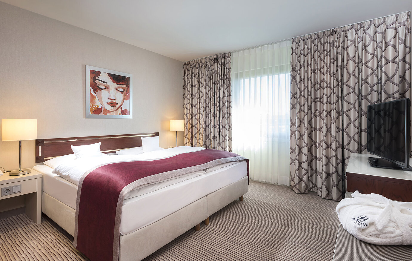 Geräumige Suite im Maritim Hotel Bonn mit gemütlichem Doppelbett, moderner Einrichtung und weinrotem Bettläufer.