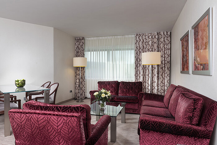 Helle und geräumige Familiensuite im Maritim Hotel Bonn mit modernen Möbeln und gemütlicher Sitzgelegenheit.