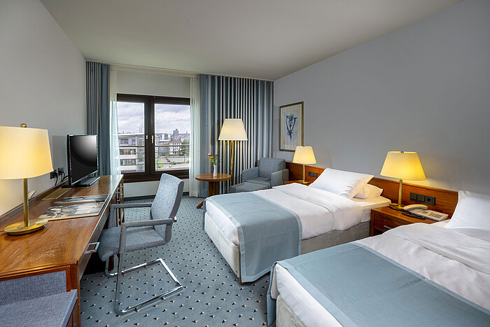 Comfort Twin Zimmer im Maritim Hotel Darmstadt mit Schreibtisch, zwei Einzelbetten und Panoramafenster mit Stadtblick.