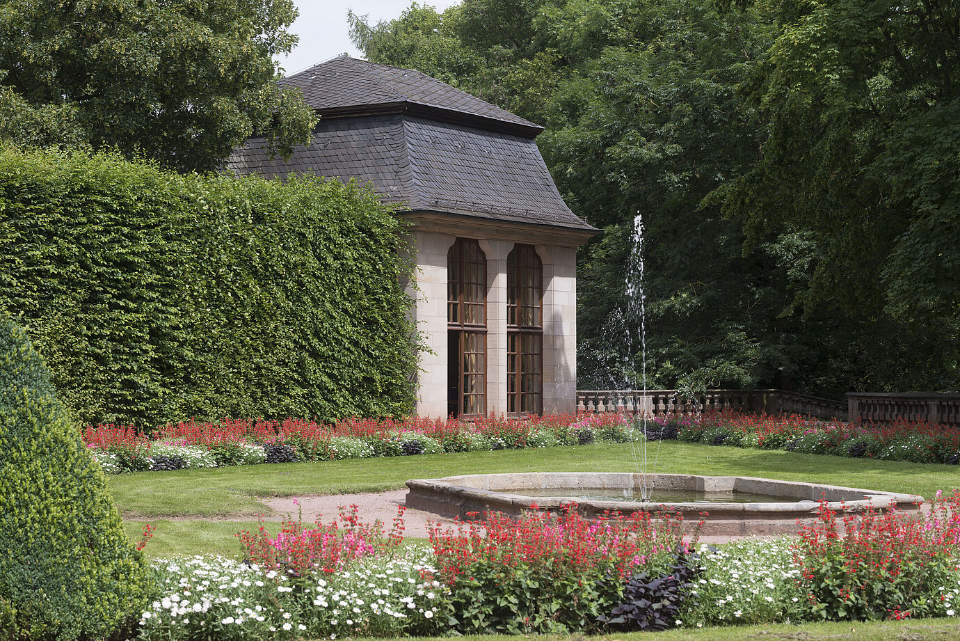 Historischer Pavillon im blühenden Garten des Maritim Hotel Fulda mit Wasserspiel und Springbrunnen.