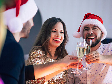 © Maksym Provozniuk - AdobeStock.com Fröhliche Weihnachtsfeier mit Freunden, Sekt und festlich gedecktem Tisch