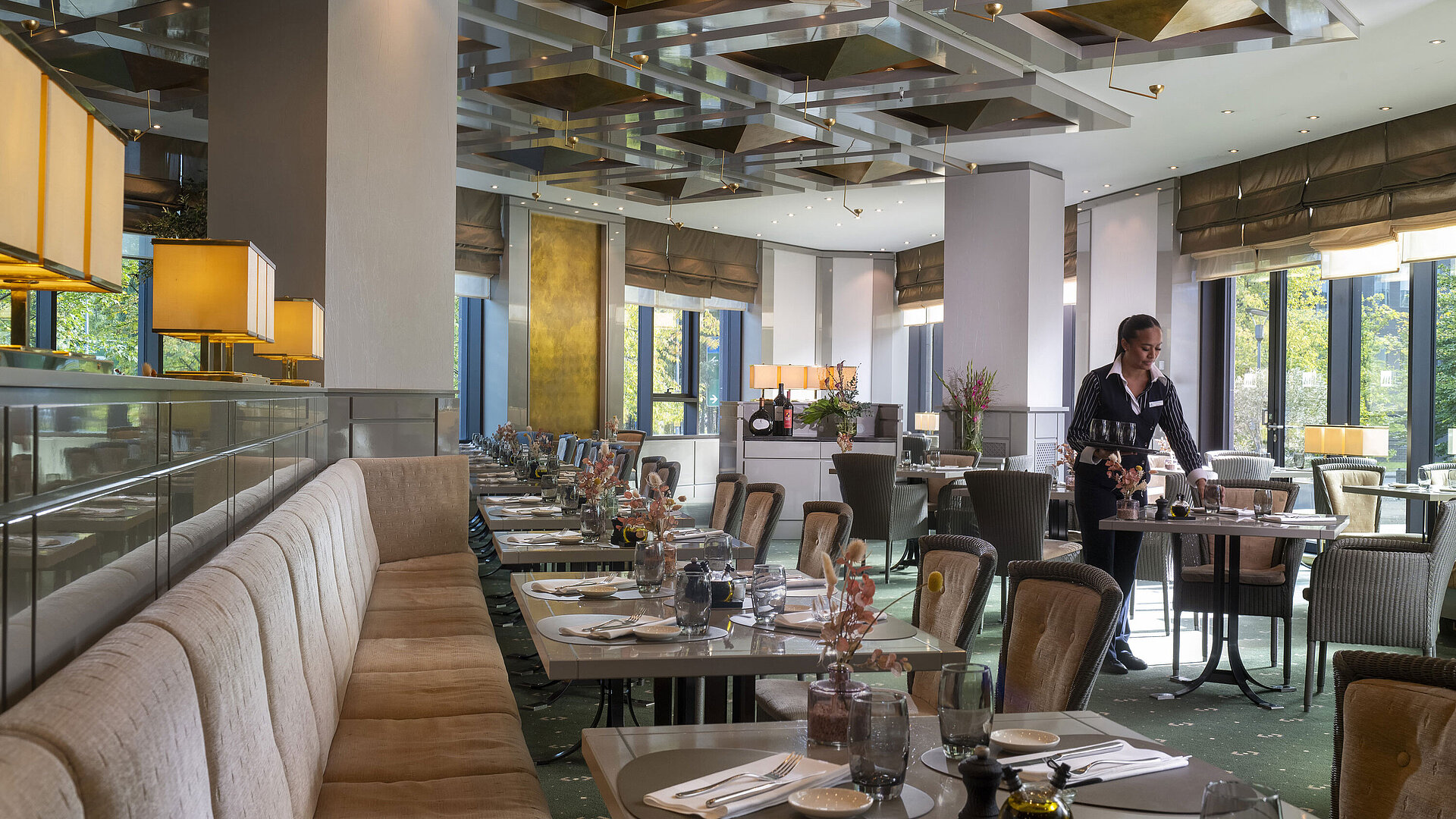Stilvoll eingerichtetes Restaurant im Maritim Hotel Düsseldorf mit gedeckten Tischen und einer Servicemitarbeiterin.