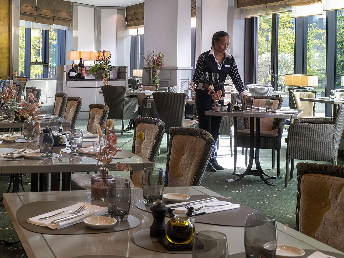 Stilvoll eingerichtetes Restaurant im Maritim Hotel Düsseldorf mit gedeckten Tischen und einer Servicemitarbeiterin.
