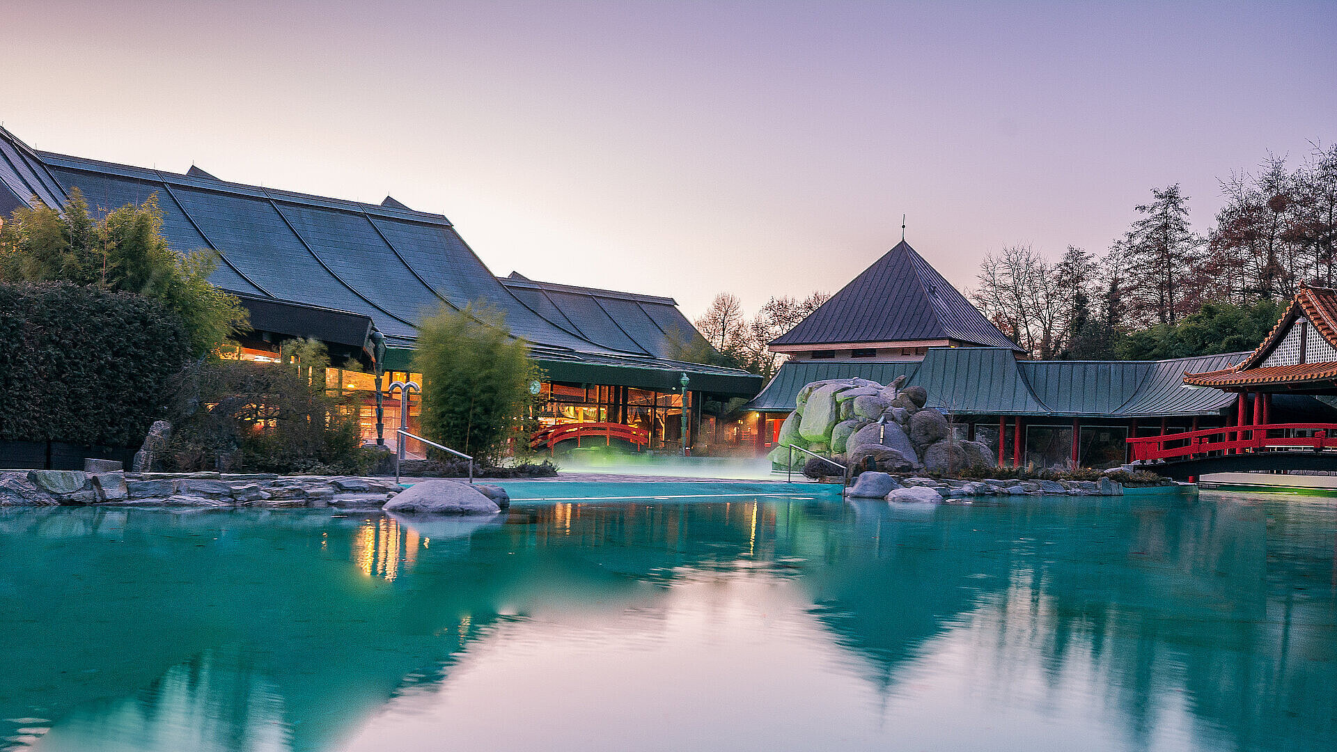 Therme mit Außenpool, asiatischer Architektur und ruhiger Wasserlandschaft bei Abendstimmung