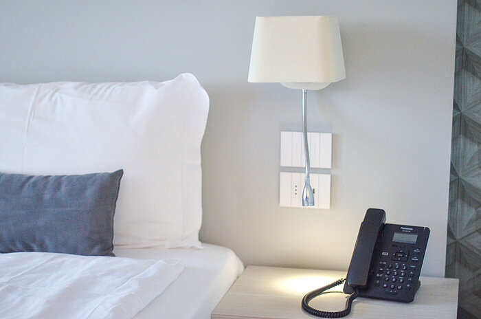 Detailaufnahme eines Nachttischs im Maritim Resort Calabria mit Telefon und LED-Leselicht