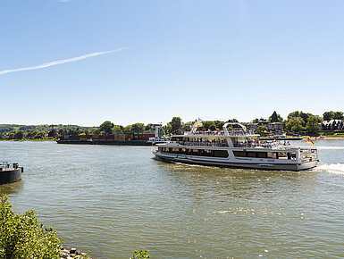 Ein Ausflugsschiff auf dem Rhein nahe Königswinter mit Blick auf die malerische Landschaft.