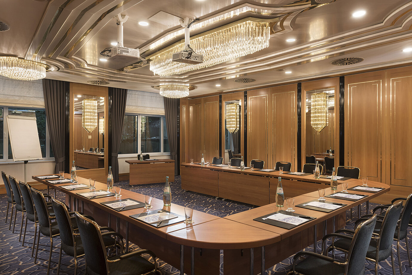 U-förmiger Tagungsraum mit eleganten Stühlen, Projektoren und Kronleuchtern im Maritim Hotel Stuttgart