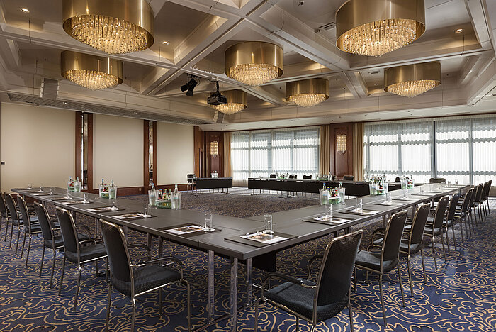 Eleganter Konferenzsaal mit U-förmiger Bestuhlung, edlen Kronleuchtern und moderner Tagungsausstattung im Maritim Hannover.