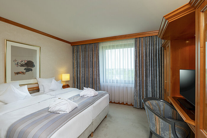 Helles Doppelzimmer im Maritim Hotel Hannover mit gemütlichem Bett und Schreibtisch.