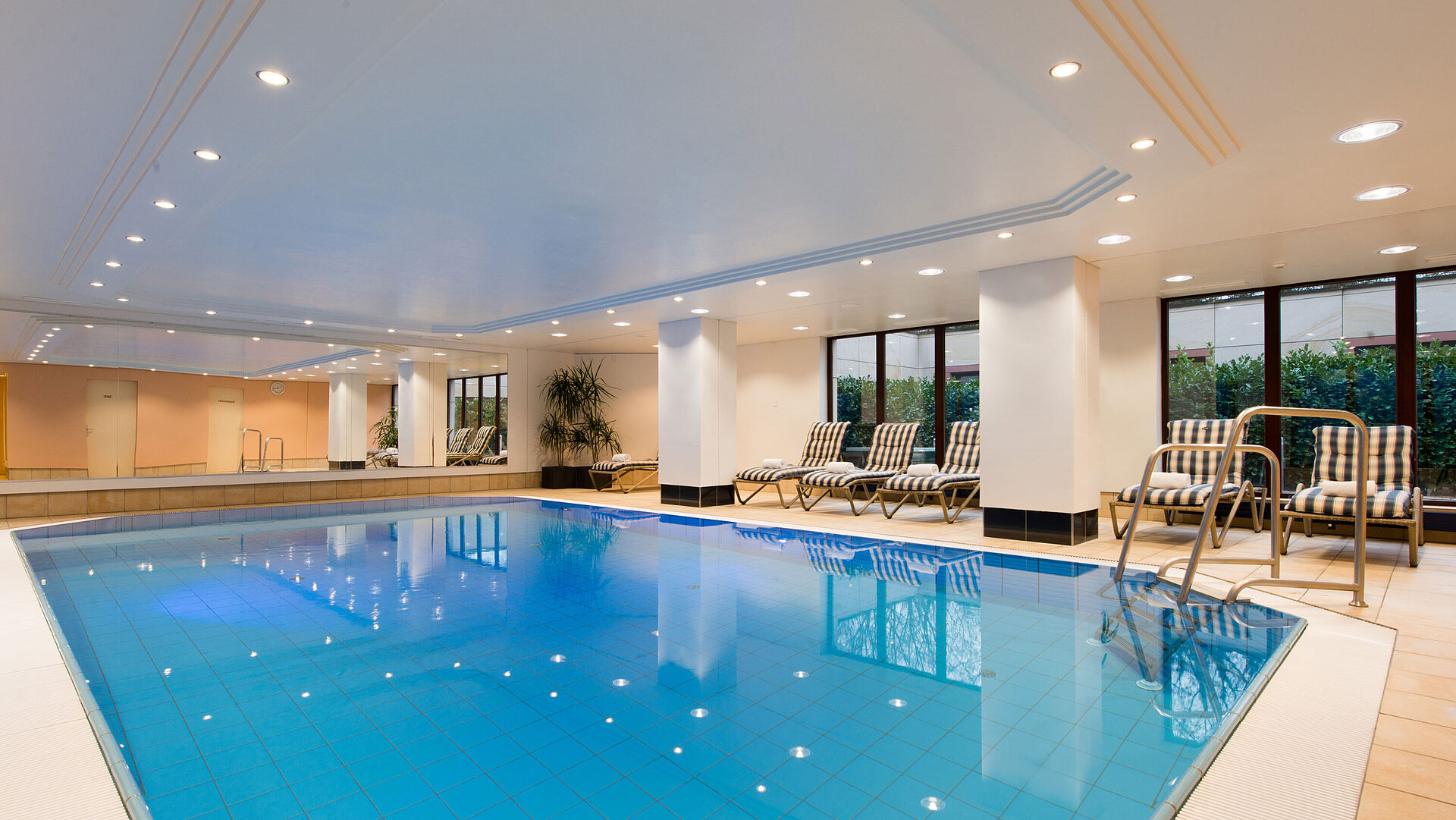 Modernes Hallenbad im Maritim Hotel Fulda mit Liegestühlen, großen Fenstern und entspannter Atmosphäre.