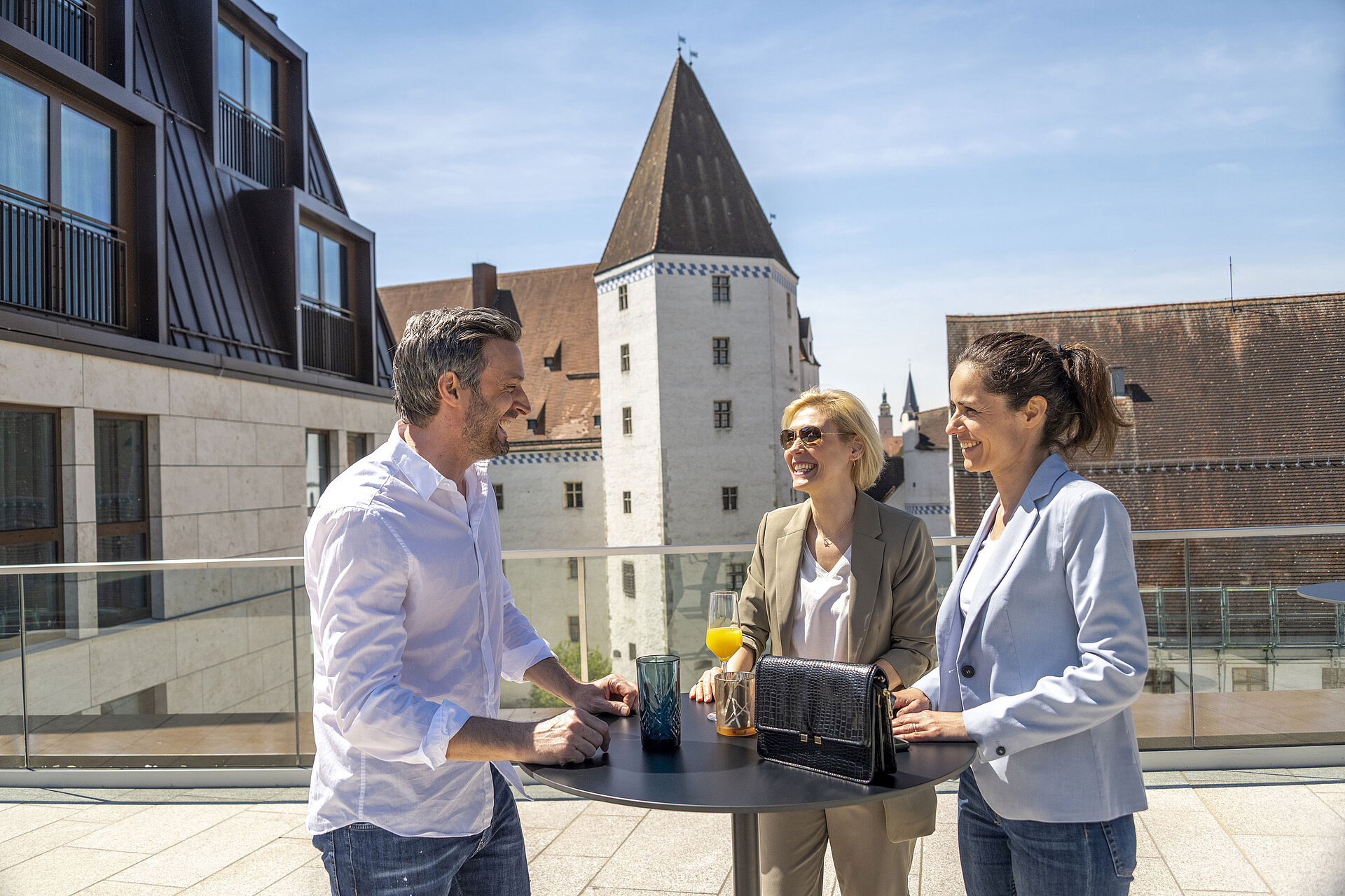 Terrasse Gäste genießen Gespräche bei Getränken auf der sonnigen Terrasse des Maritim Hotels Ingolstadt.