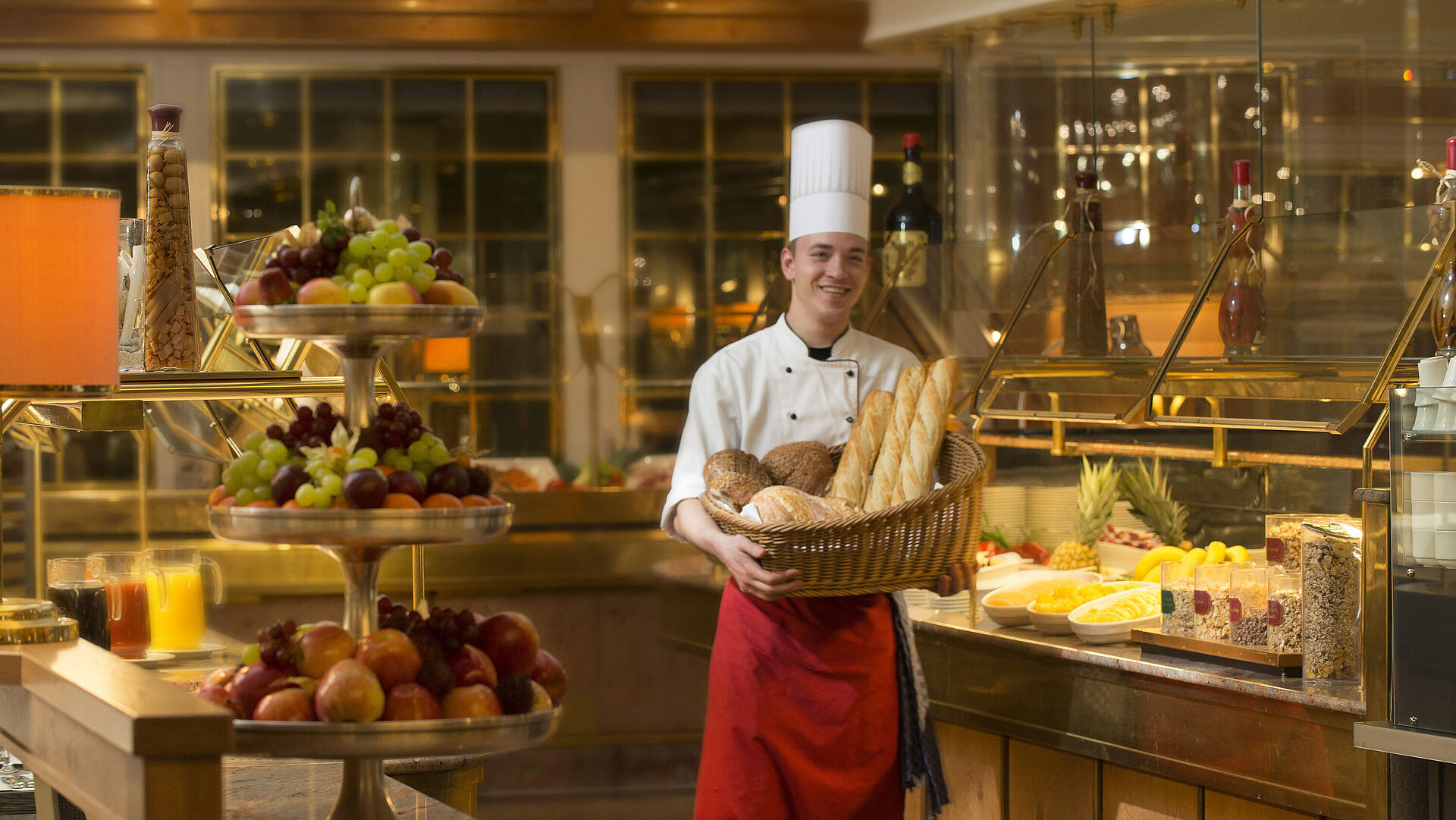 Bäcker mit Brotkorb am Frühstücksbuffet des Maritim Hotel Stuttgart, umgeben von frischem Obst