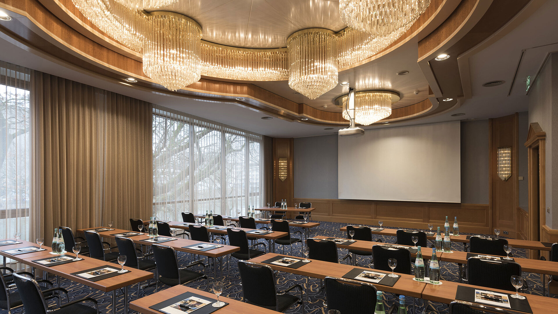 Eleganter Tagungsraum mit Reihenbestuhlung, Kronleuchtern und Projektionsfläche im Maritim Hotel Ulm.