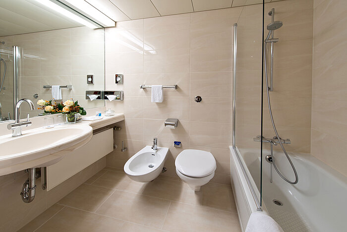Helles, elegantes Badezimmer mit Badewanne, Dusche, Waschbecken und Spiegel im Maritim Hotel Hannover.