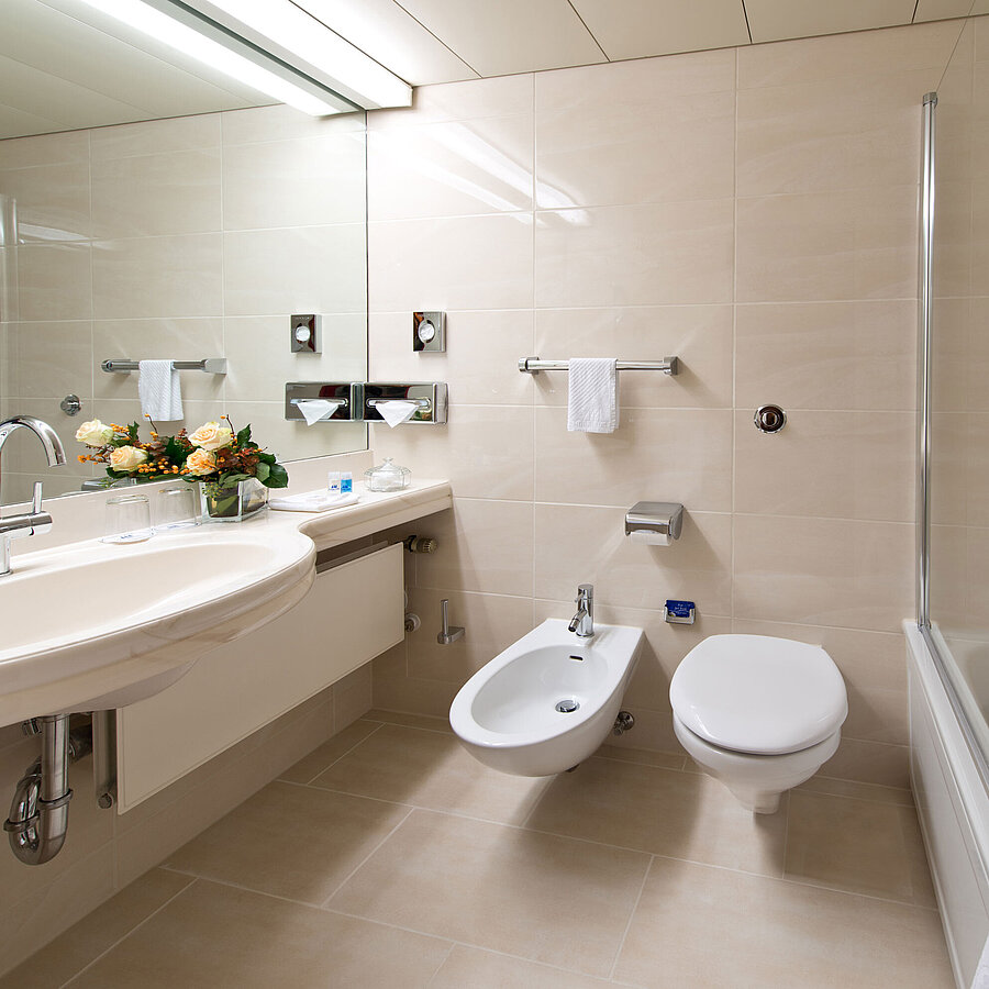 Helles, elegantes Badezimmer mit Badewanne, Dusche, Waschbecken und Spiegel im Maritim Hotel Hannover.