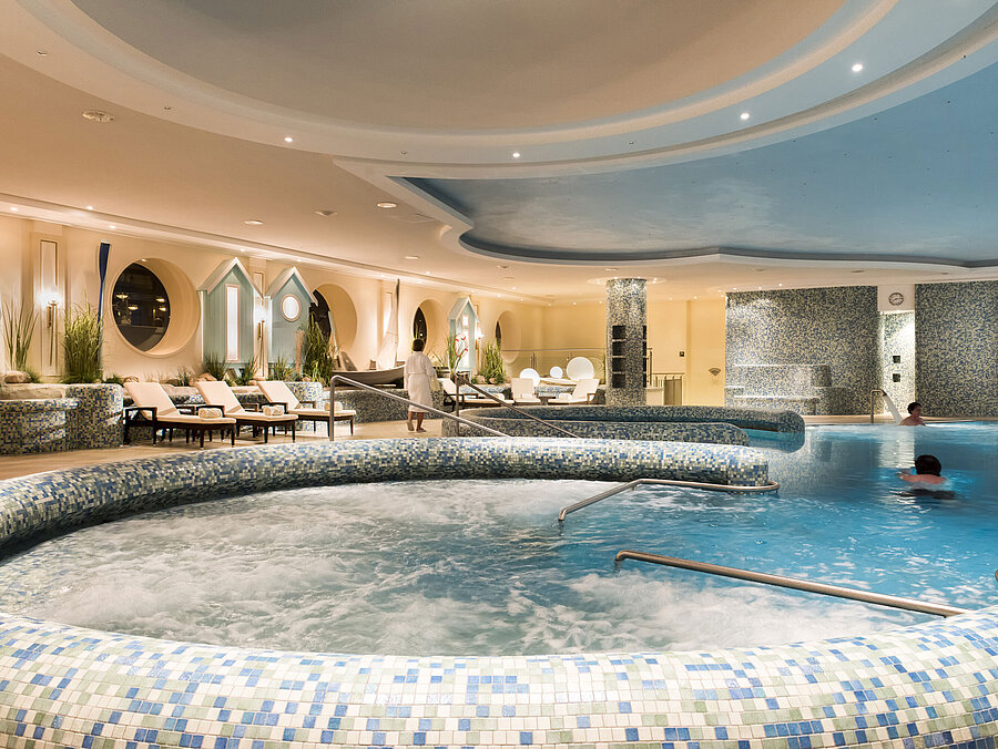 Großzügiger Wellnesspoolbereich mit Whirlpool und Liegestühlen im Maritim Seehotel Timmendorfer Strand.
