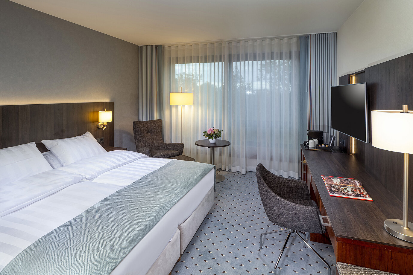 Modernes Superior Doppelzimmer im Maritim Bremen mit Sitzbereich, Schreibtisch und großem Fenster für natürliche Beleuchtung.