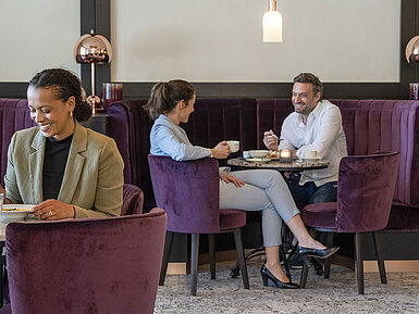 Gäste genießen eine gemütliche Kaffeepause in der stilvollen Lounge des Maritim Hotel Ingolstadt.
