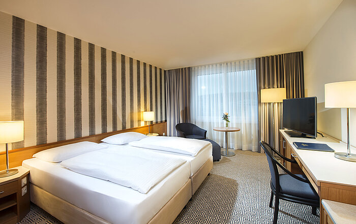Modern eingerichtetes Doppelzimmer mit Schreibtisch, Fernseher und Tageslicht im Maritim Hotel Stuttgart
