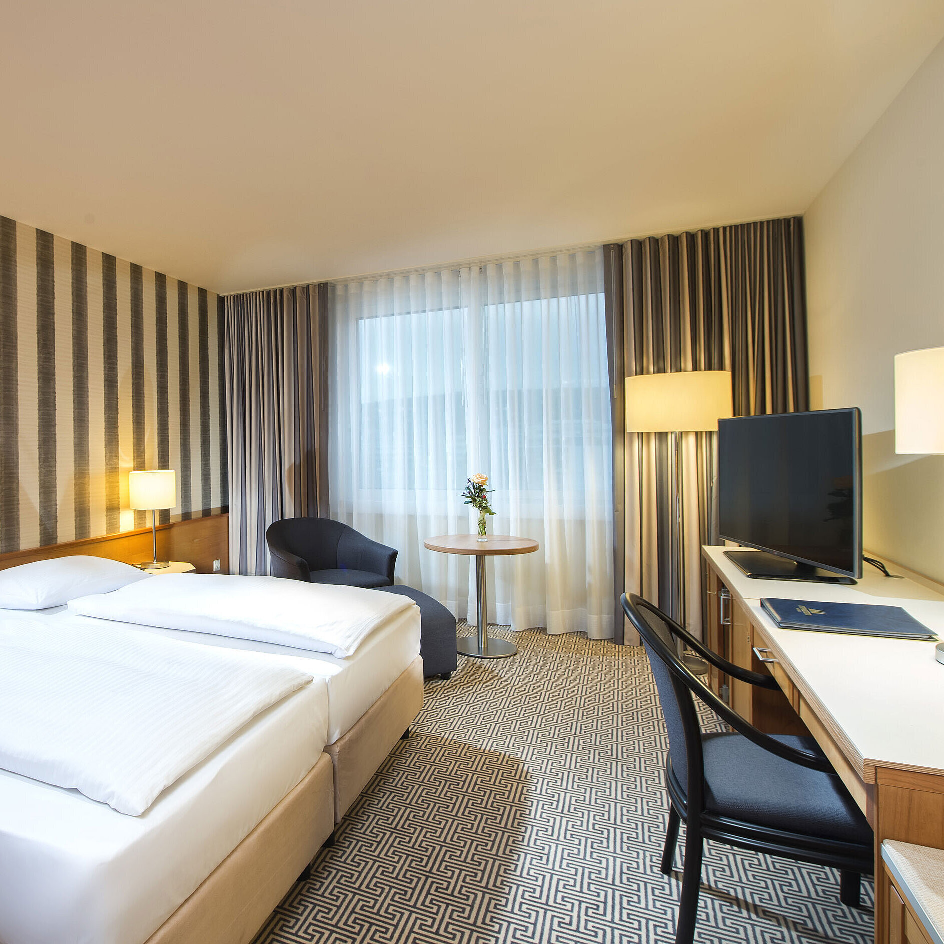 Modern eingerichtetes Doppelzimmer mit Schreibtisch, Fernseher und Tageslicht im Maritim Hotel Stuttgart